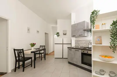 a white kitchen with a table and chairs and a counter at San Giovanni Home in Rome
