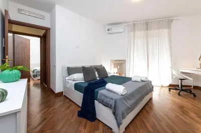 a white bedroom with a bed and a desk at SkyView Home in Rome