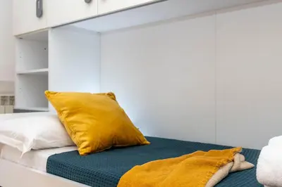 a bed with a yellow pillow on top of it at SkyView Home in Rome