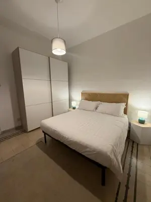 a bedroom with a white bed with two lamps on it at Pietra Apartment,Colosseo in Rome