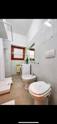 a white bathroom with two toilets and a sink at Anastasio II apartment in Rome