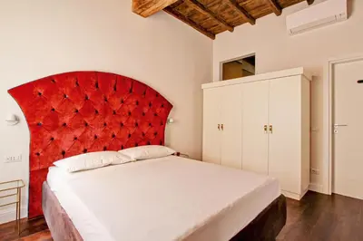 a bedroom with a red headboard and white cabinets at CoroCoro114 Comfort ed Eleganza in Rome