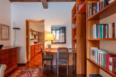 a room with a table and chairs and bookshelves at GuestHost - Campo de Fiori Unique Apartment in Rome