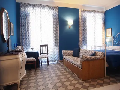 a bedroom with blue walls and a bed and a chair at Le Stanze di Pietro in Rome