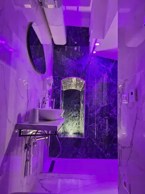 a bathroom with a sink and purple lighting at Mirror Suite Roma Colosseo Monti con Jacuzzi in Rome