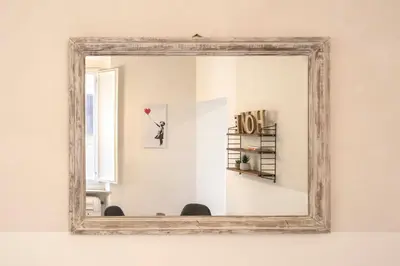 a mirror with a wooden frame on a wall at Cinque Loft in Rome