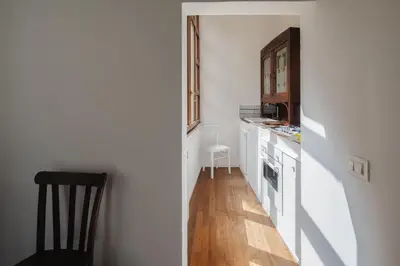 a small kitchen with white cabinets and a wooden floor at Dadi Inn Monti in Rome
