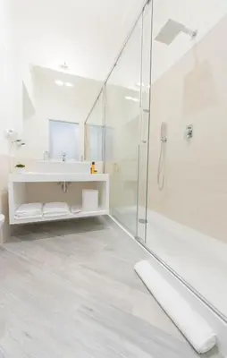 a white bathroom with a shower and a sink at Vantaggio Suites in Rome