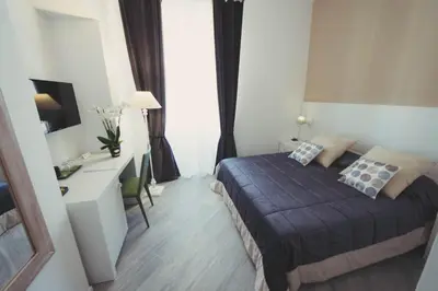 a bedroom with a bed and a desk and a television at Vantaggio Suites in Rome