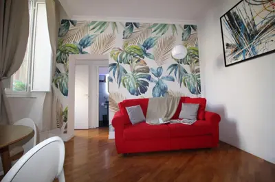 a red couch in a living room with a tropical wallpaper at LPR Pantheon - Stylish Apartment at the Pantheon in Rome