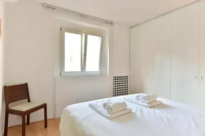 a white bedroom with a bed and a chair at Appartamento Piazza Navona in Rome
