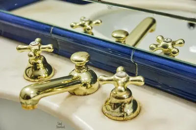 a bathroom sink with brass faucets and a mirror at iFlat Magnificent flat near the Colosseum in Rome