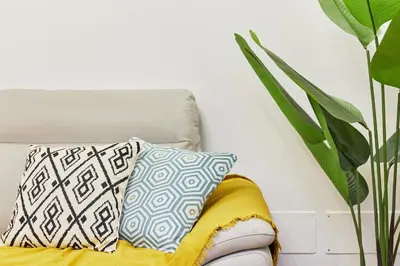 a white couch with two pillows on it next to a plant at iFlat Magnificent flat near the Colosseum in Rome