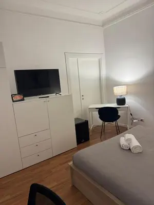 a bedroom with a bed and a desk with a television at Be Your Home - Mazzini 144 in Rome