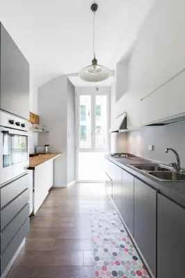 a kitchen with white cabinets and a wooden floor at Casa Esquilina in Rome