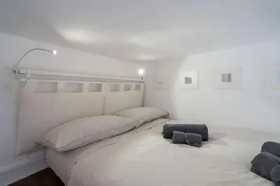 a white bedroom with a large bed and a chair at Piazza Navona - Tiny House in Rome