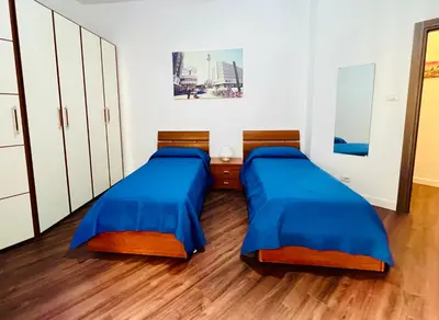 two beds in a room with wooden floors and white cabinets at Elegant Apartment Villa Bianca in Rome