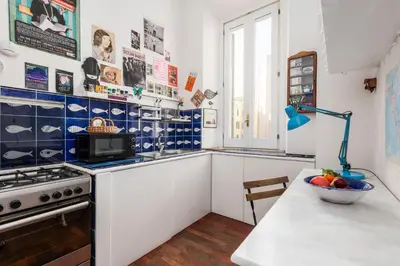 a kitchen with white cabinets and a bowl of fruit on a table at Colosseum Home-ZENO 32 in Rome