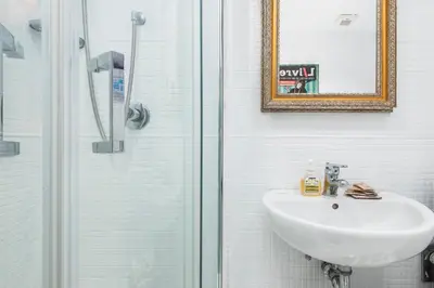a white bathroom with a sink and a shower at Colosseum Home-ZENO 32 in Rome