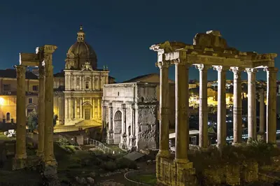 an old building with columns and a cathedral at night at San Vito Suites in Rome