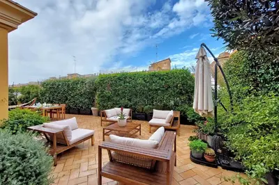 a patio with chairs and an umbrella and tables at LuxuryTerrace RomeApartment in Rome