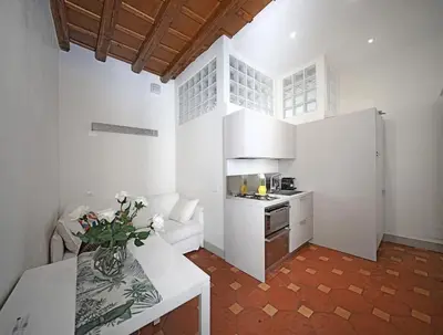 a kitchen with white walls and a table with flowers on it at Suite Valeria in Rome