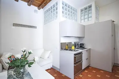 a white living room with a white couch and a kitchen at Suite Valeria in Rome