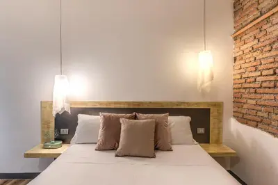a bedroom with a white bed with a brick wall at Suite San Calisto Trastevere - by romanhouseit in Rome