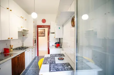a kitchen with white cabinets and black counter tops at San Pietro Intero Alloggio -PANE&MELE- in Rome