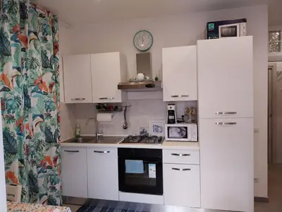 a small kitchen with white cabinets and a clock on the wall at Il giardino di Marimar in Rome