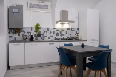 a kitchen with a wooden table and blue chairs at TrastevereLoft228 Apt. WHITE in Rome