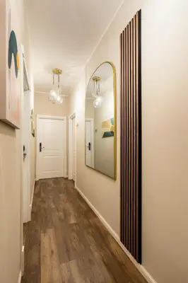 a hallway with white walls and a mirror and wood floors at AlbaDea Déco&Jacuzzi in Rome