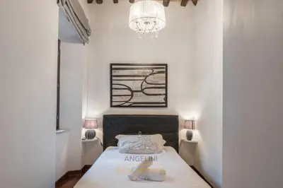 a small bedroom with a bed and a chandelier at Apartment by The Spanish Steps in Rome