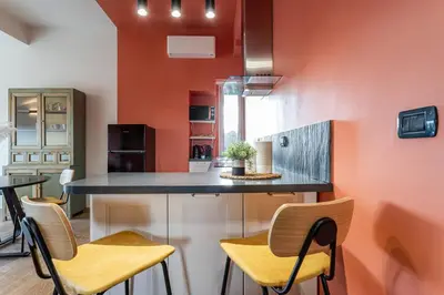 a kitchen with orange walls and a counter with chairs at Viola Penthouse with Rome Panoramic View in Rome