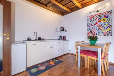 a kitchen with white cabinets and a table with chairs at ht bilo colosseo in Rome