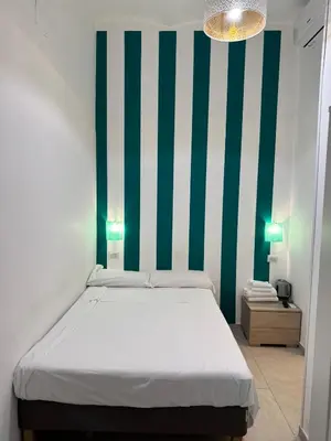 a bedroom with a bed with a green and white stripe wall at TERMINI STAR in Rome