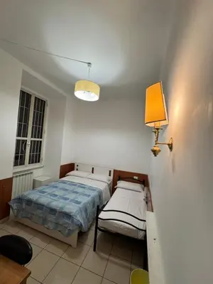 a bedroom with two beds and a lamp on the wall at TERMINI STAR in Rome