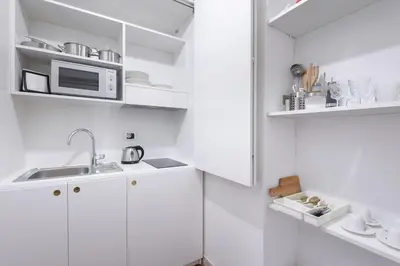 a white kitchen with a sink and a microwave at Discover the Pantheon from The Berardi Studio Flat in Rome