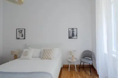 a white bedroom with a bed and a chair at Elegant apartment with patio at Piazza Navona in Rome