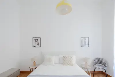a white bedroom with a bed and two chairs at Elegant apartment with patio at Piazza Navona in Rome