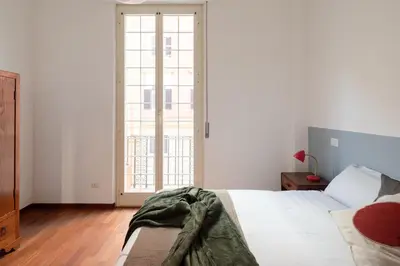 a white bedroom with a bed and a large window at Nuovo appartamento a S. Lorenzo con 3 camere in Rome