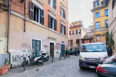 a street with a car and a scooter parked next to a building at Brightful Boutique Apartment in the Heart of Trastevere in Rome