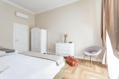 a white bedroom with a bed and a chair at Daplace - Livia Apartment in Rome