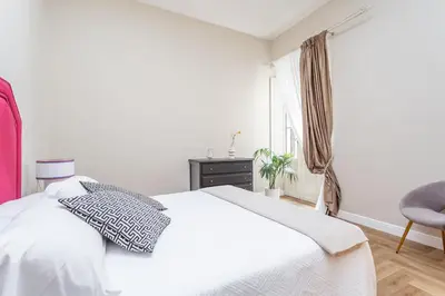 a white bedroom with a bed and a chair at Daplace - Livia Apartment in Rome