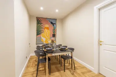 a dining room with a table and chairs and a painting at Daplace - Livia Apartment in Rome