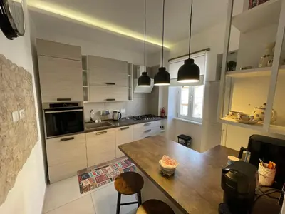 a kitchen with white cabinets and a wooden table at San Paolo Inn in Rome