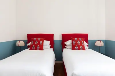 two beds in a room with red and blue walls at Casa Angelica, a Burghesius home in Rome