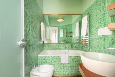 a green tiled bathroom with a tub and a sink at Casa Angelica, a Burghesius home in Rome