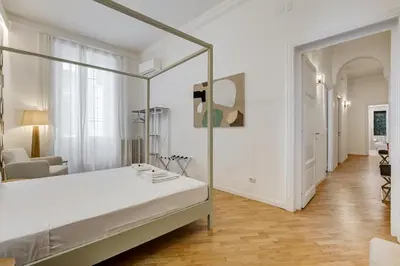 a white bedroom with a bed and a chair at BMGA l Gracchi Lux Lovely 3Bdr Apartment in Rome