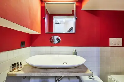 a bathroom with a white sink and a red wall at iFlat Marvellous home near Via del Corso in Rome